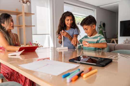Hispanic family helping kids learn and craft at home