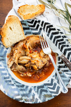 Rustic pig's feet stew with bread on patterned plate
