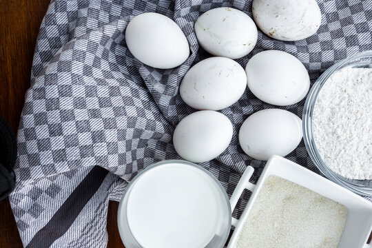 Baking ingredients on checkered towel with eggs and flour