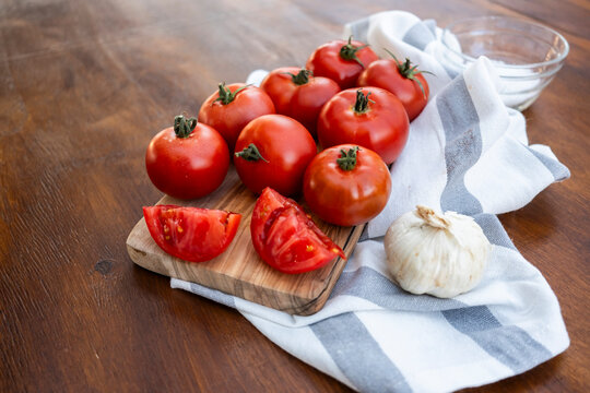 Fresh tomato and garlic on cutting board on wooden table