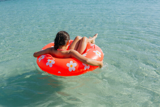 rear view of a girl floating on swimming ring in the sea