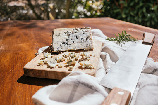Rustic blue cheese on wooden board with knife outdoors