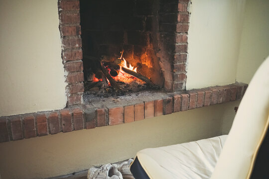 Cozy living room fireplace with burning logs and brick