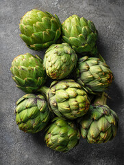 Fototapeta premium A fresh bunch of green artichokes with textured leaves neatly arranged on a dark gray stone surface creating a natural and healthy vegetable display