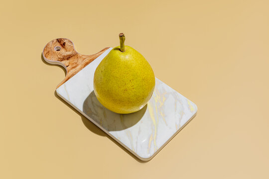 Pear on marble cutting board on beige background