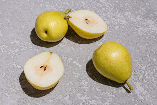 Fresh pear halves and whole fruit on gray stone surface