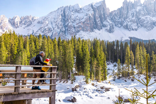 Winter view at Carezza Lake with hikers in Alto Adige