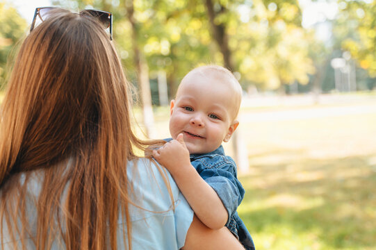 Mother holding smiling son in sunny park outdoors