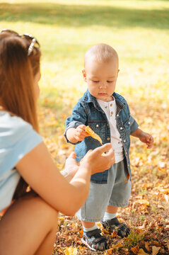 Mother and young son in park sharing an autumn leaf