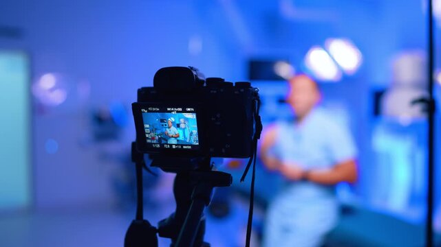 Camera Screen Shows Doctor Recording Vlog In Clinic. Camera screen shows doctor in scrubs, blurred clinic background, blue lighting and shallow depth of field.