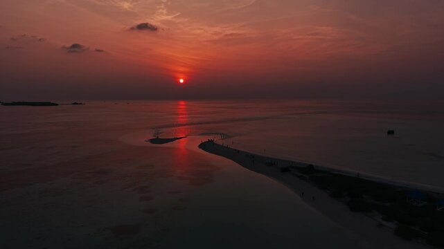 Sunset over Maldives sandbank with calm ocean and clouds