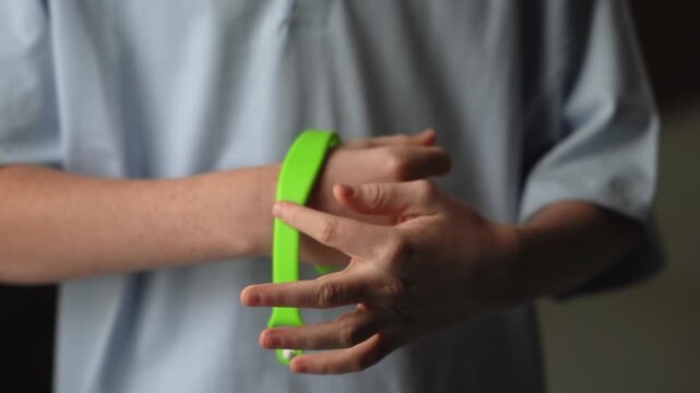 A teenager in a hotel room puts on an RFID or NFC bracelet. A boy puts on a contactless bracelet on his wrist. High quality FullHD footage