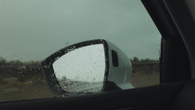 Rainy day view through car window with wet side mirror