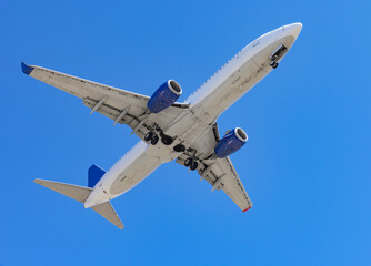 Obraz premium A passenger airplane flying in a clear blue sky. View of the airplane from below showing its underside.