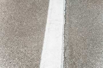 Obraz premium Top view of cracked asphalt road with white painted dividing line. Concept foto of the road.