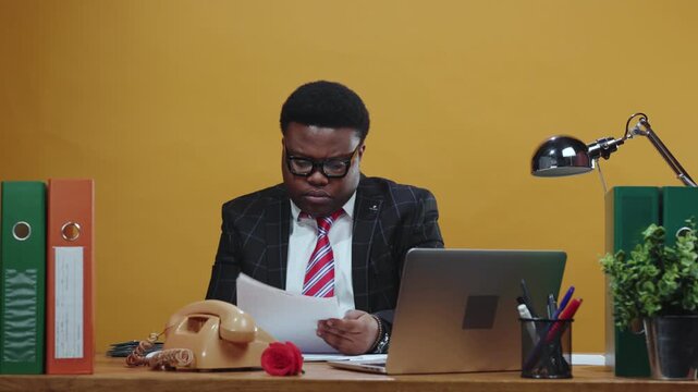 A focused professional diligently working at a desk with a laptop and various office supplies