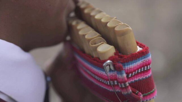 A young man plays a long zampo&ntilde;a or situ with great skill. The pipes of the zampo&ntilde;a are held together by an ornament made of red, blue, and white sheep's wool, a traditional Andean decoration.