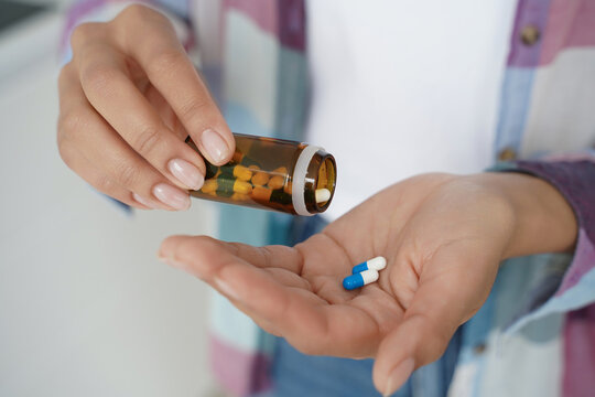 Woman pouring pills from medicine bottle into hand for daily medication