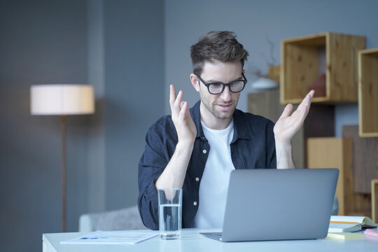 Frustrated man reacting to laptop problem during online meeting at home