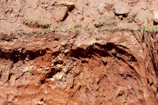 Excavation in red soil with ground cutting for foundation preparation at a construction site.