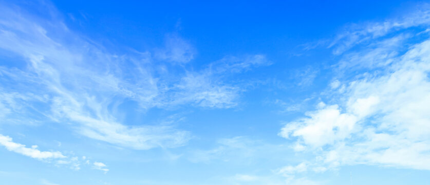 Panoramic blue sky background with white wispy clouds and bright sunlight for natural backdrop and clean outdoor design