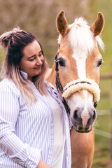 Fototapeta premium Young woman cuddling Haflinger mare with gentle connection and emotional bond in natural outdoor setting