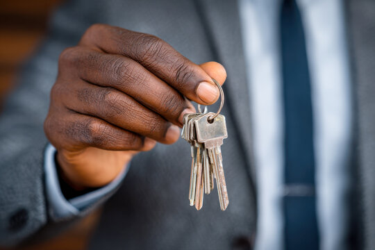 Businessperson holding a set of old silver keys in hand symbolizing access, security, and control over property or important opportunities in a professional setting