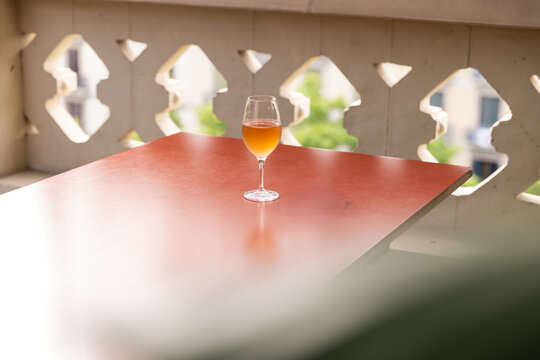 Glass of orange wine on table with patio overlooking city with plants in foreground 