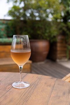 Glass of orange wine on wood table in outdoor patio 