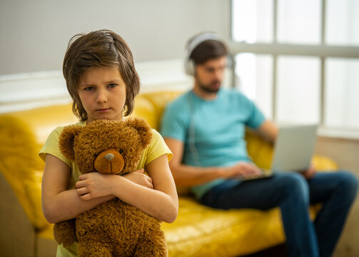 Upset boy holding teddy bear at home