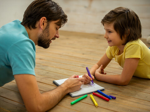 Father teaching child drawing.