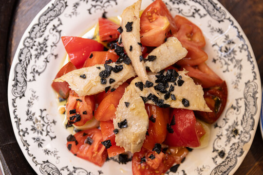 catalan tomato and tuna salad with olive oil, herbs, and glass of vermouth in spain, outdoor dining