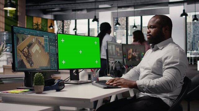 Green screen and architectural software on dual monitors in creative agency, apartment floor plan with remodeling program. Black man developing layout and 3D rendering of interior design.