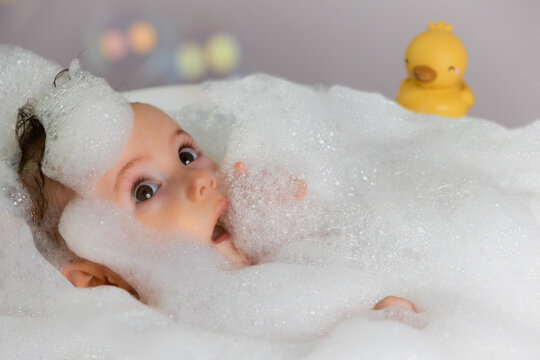 Happy baby enjoying bubble bath with toy duck