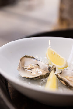 oysters served with lemon over ice in white bowl