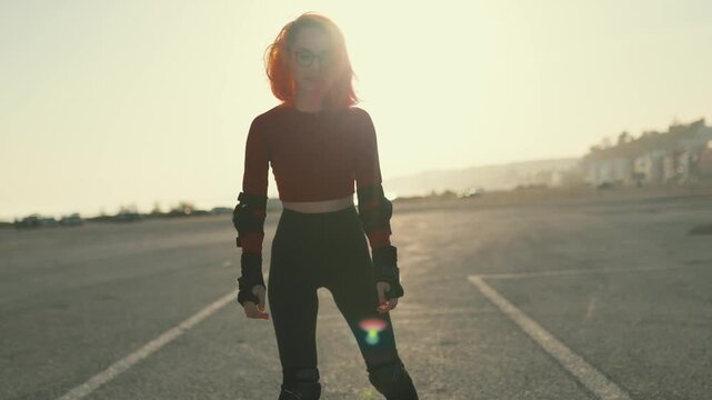 Young woman with red hair rollerblading at sunset