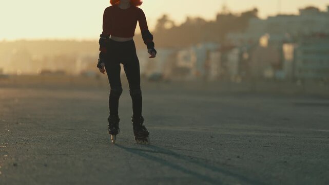 Young woman rollerblading on asphalt at sunset