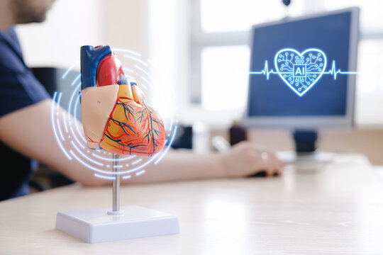 Medical education desk scene with anatomical heart model and assistant ai cardiology interface on monitor