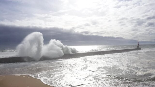 Huge waves crashing over Breakwater during winter storm Atlantic waves washing the lighthouse on Praia da Aguda sandy beach at Aguda settlement near Porto, Portugal. Incredible 4K flying drone video.