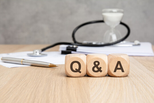 Q and A text on wooden blocks with stethoscope and hourglass