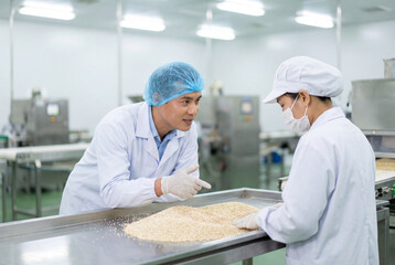 Obraz premium Male and female quality control workers inspecting grains in factory