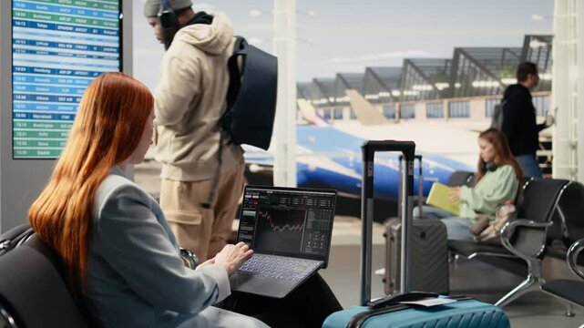 Independent female trader checking financial data and currency exchange, investment performance on laptop in airport waiting area. Busy terminal emphasizes remote trading and nomadic lifestyle.