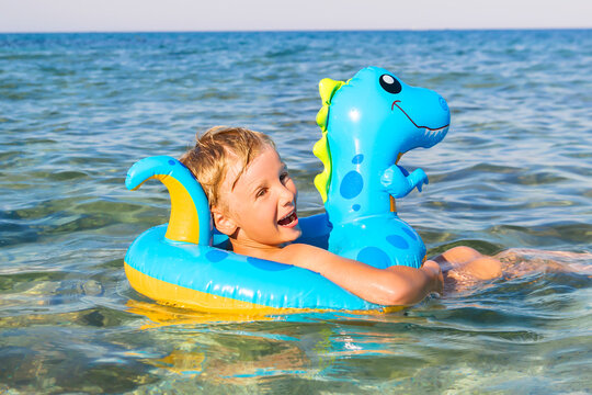 Child boy on inflatable float ring swimming enjoying in sea.Summer vacation,healthy outdoor sport activity for children.Kids beach fun.Water toy
