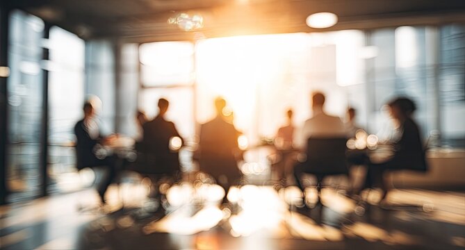 A blurred, warm-toned image depicts a group of silhouetted figures seated around a conference table in a modern office setting, suggesting a business meeting or discussion.