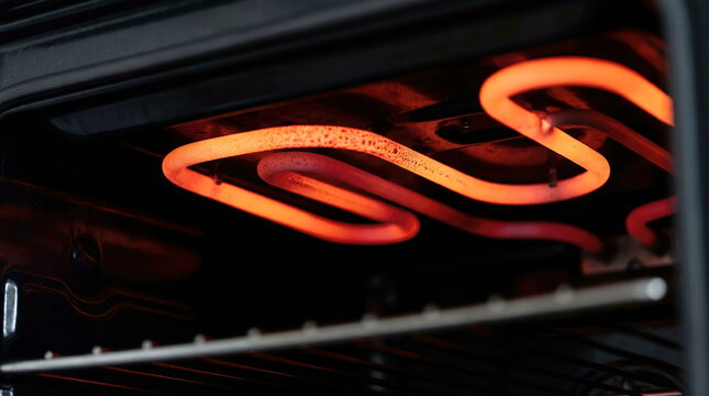 Electric oven heating element glowing bright orange-red inside domestic kitchen appliance, symbolizing warmth and cooking preparation.
