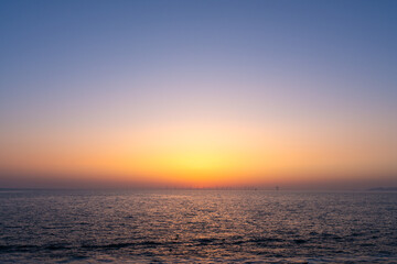 Fototapeta premium Minimalist Seascape with Golden Sunset Gradient and Distant Wind Farm