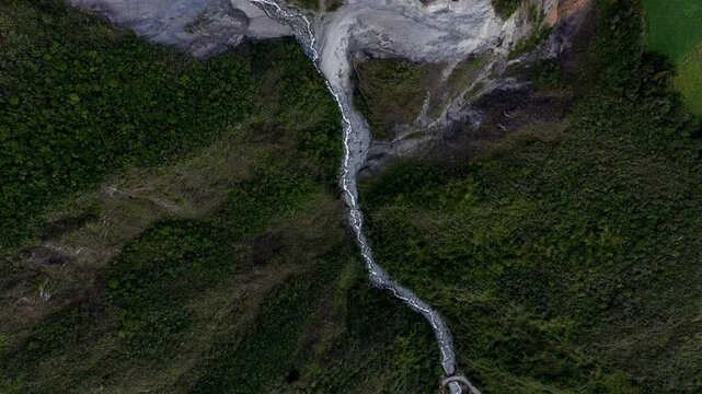 Aerial top down view of a small mountain stream running through the rough landscape, abstract background