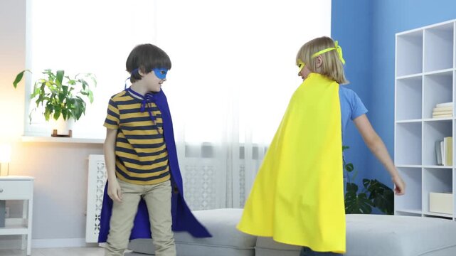 Little boys in superhero costumes playing together at home. Camera moving