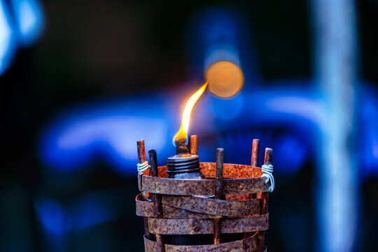 Close-Up of a Burning Bamboo Tiki Torch with Flickering Orange Flame, during twilight.