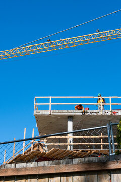 Construction worker high up on building project working on grouting structural post-tensioning wire strand holes running through concrete slab of floor

